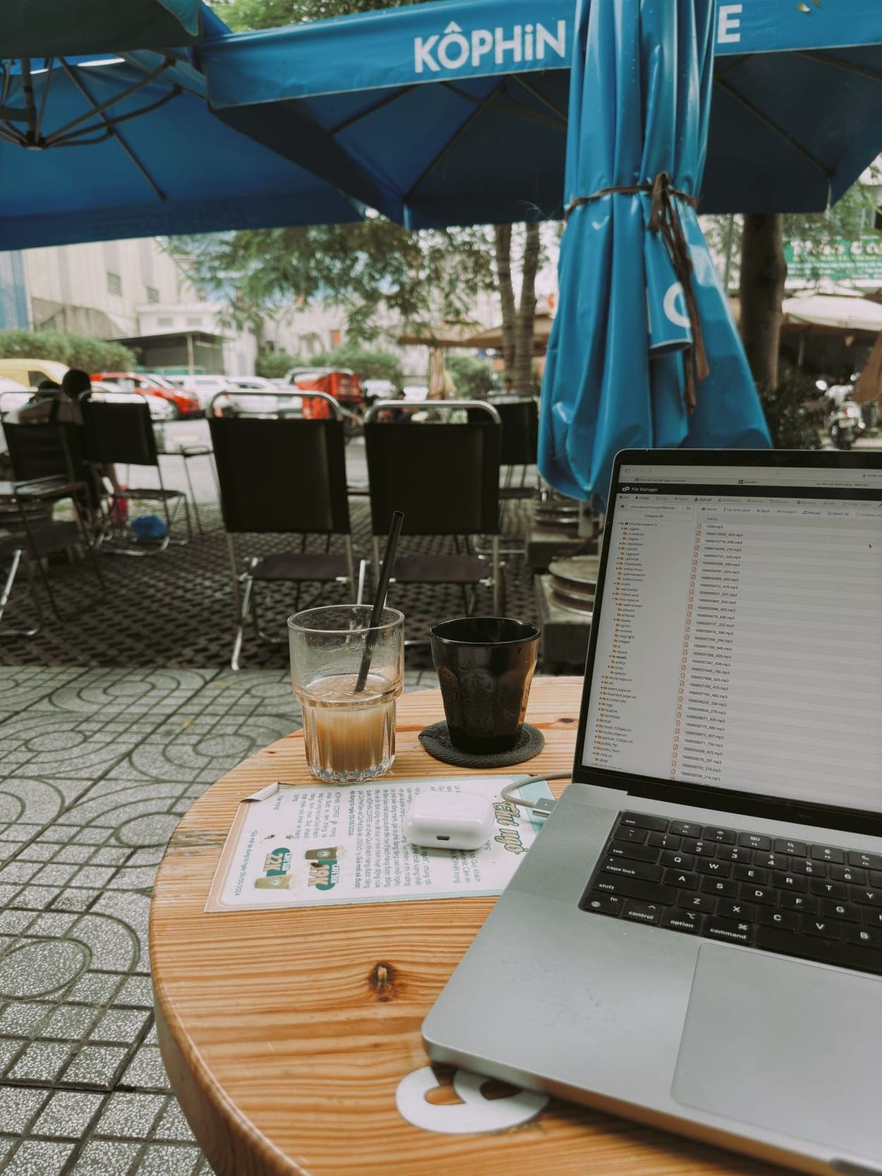 A laptop and coffee on a sunny outdoor café table (illustrative photograph)