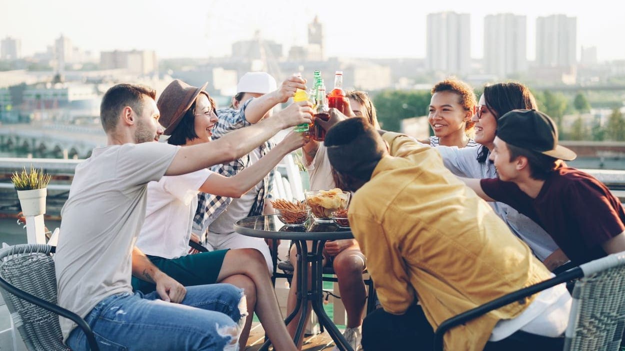 A relaxed group of young professionals chatting at a rooftop gathering (illustrative photograph)